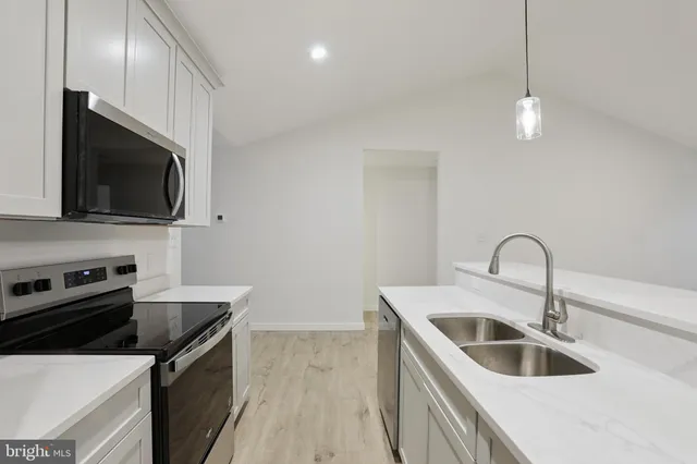 a kitchen with a sink and a stove top oven with wooden floor