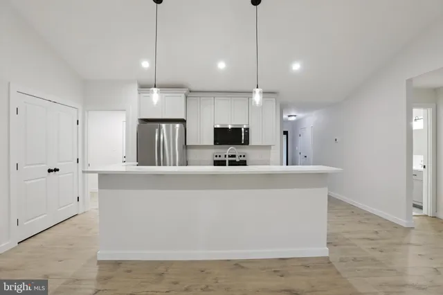 a view of kitchen with center island and stainless steel appliances with cabinets