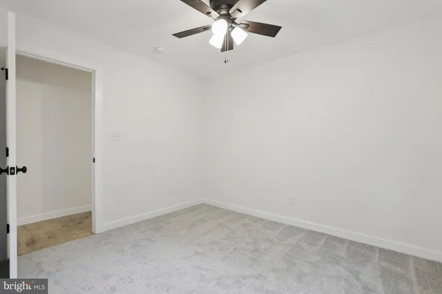 a view of an empty room with a chandelier fan