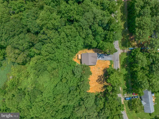 an aerial view of residential house with outdoor space and trees all around