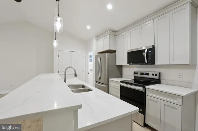 a kitchen with stainless steel appliances a stove a sink a refrigerator and white cabinets