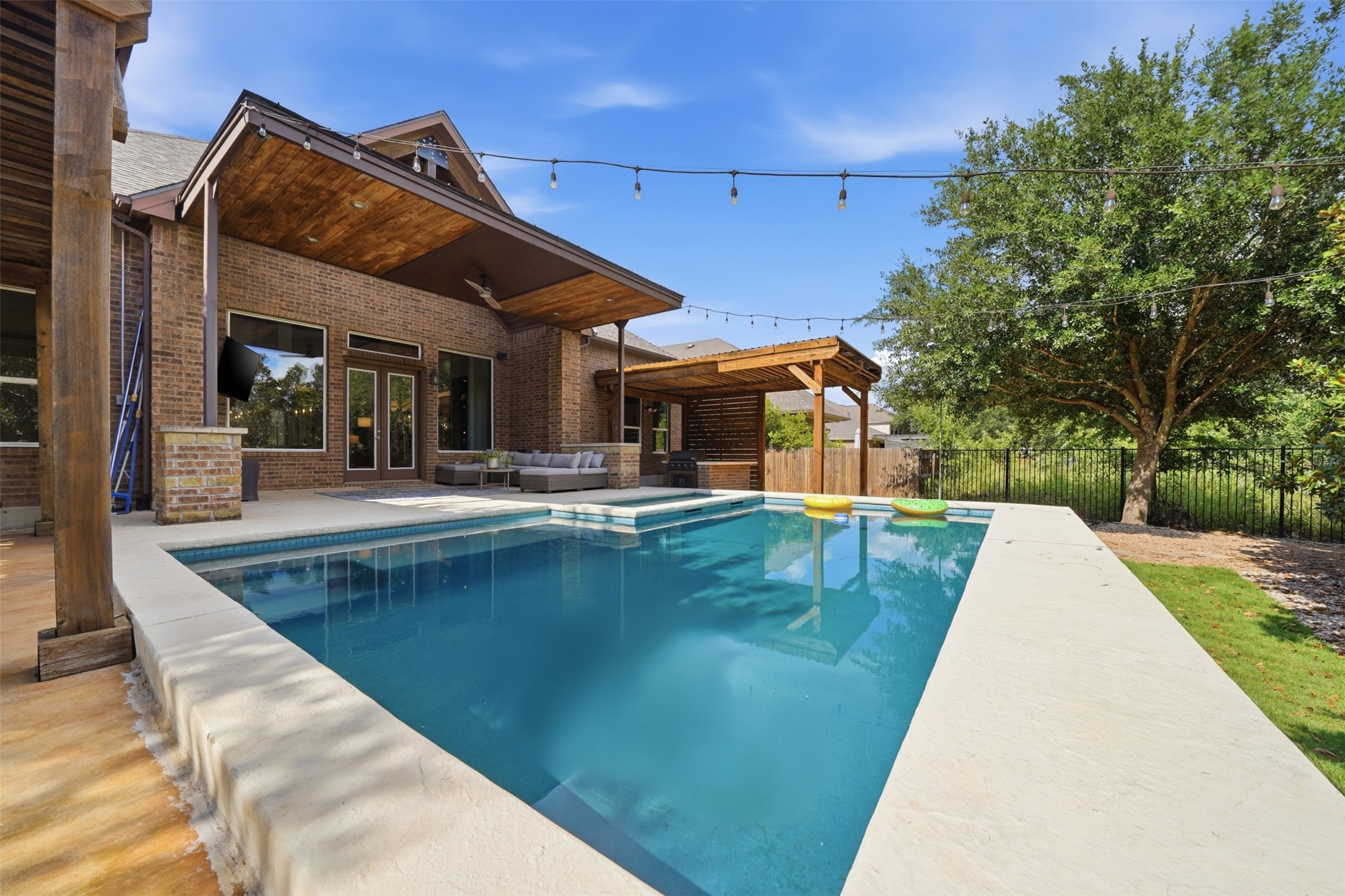 8729 Vantage Point Drive Austin, TX 78737 - Photo 25 of 33 Lush landscaping and string lights illuminate a sparkling pool, perfect for evening entertainment.
