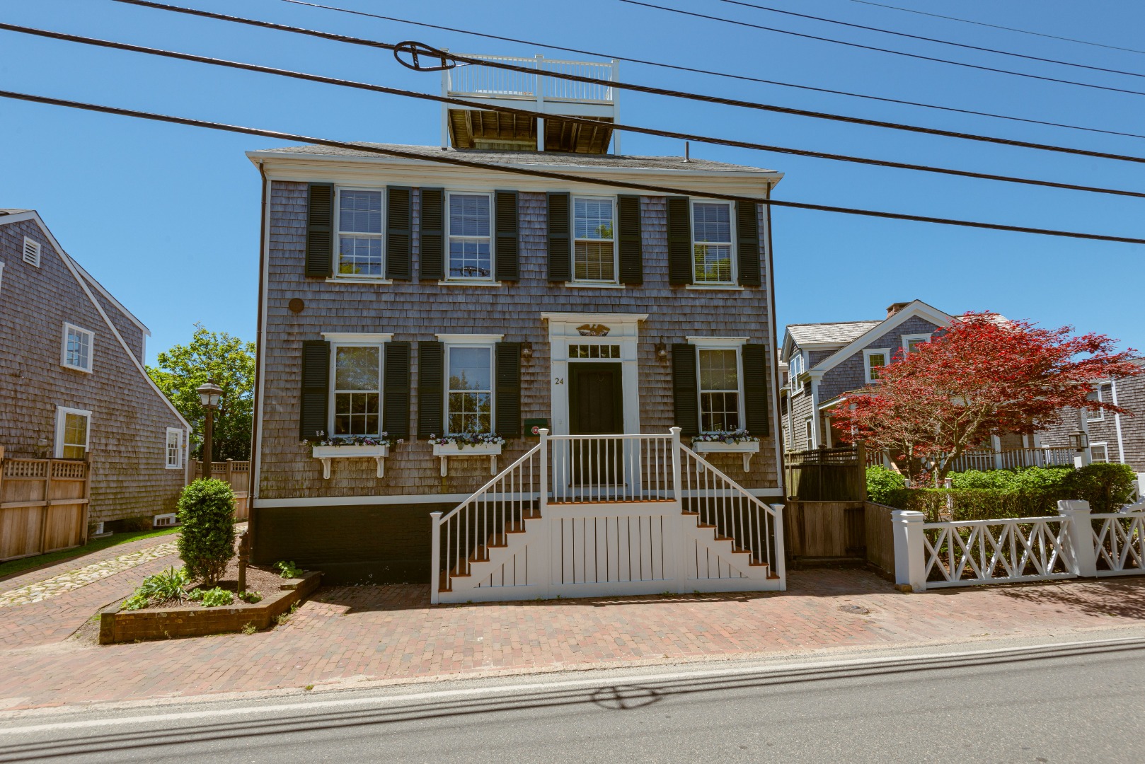 24 Cliff Road Nantucket, MA 02554 - Photo 2 of 44 a view of a brick house with large windows and a small yard