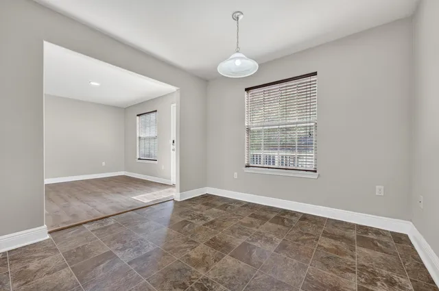 a view of an empty room with window and chandelier fan
