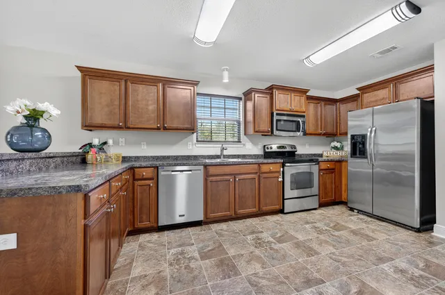 a kitchen with stainless steel appliances granite countertop a stove a sink dishwasher a refrigerator and a microwave