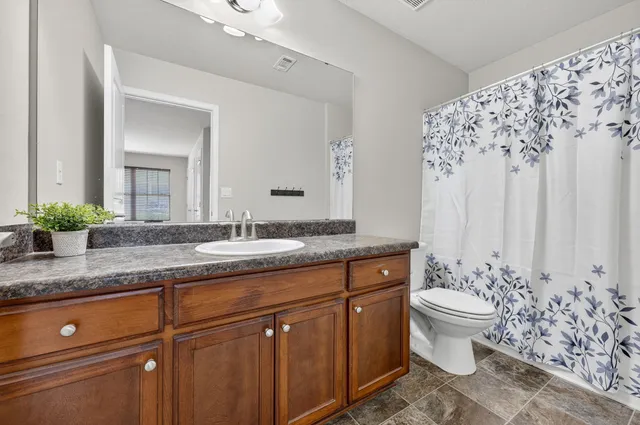 a bathroom with a granite countertop sink and a toilet