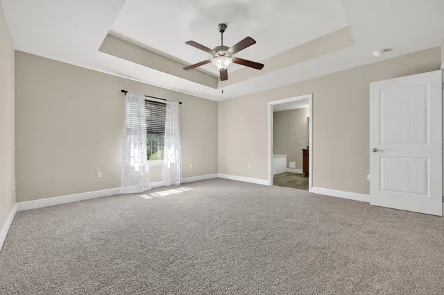 an empty room with ceiling fan and window