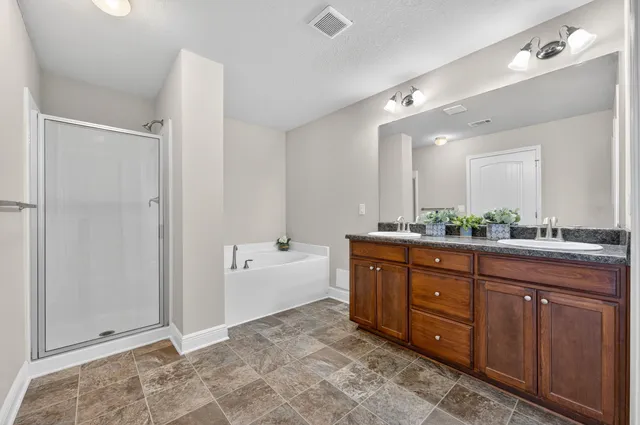 a spacious bathroom with a tub sink shower and mirror