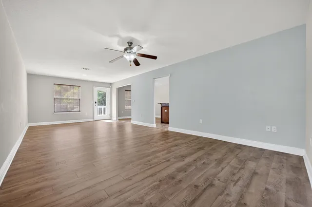 a view of empty room with wooden floor and fan