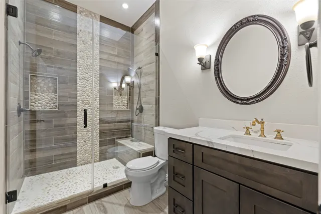 a bathroom with a toilet a sink a mirror and shower