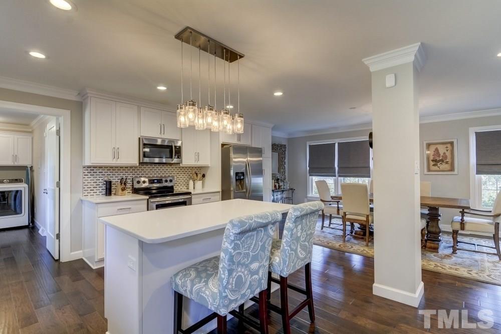 3005 Old Orchard Road Raleigh, NC 27607 - Photo 9 of 21 a kitchen with stainless steel appliances a stove top oven a refrigerator a sink dishwasher a dining table and chairs with wooden floor