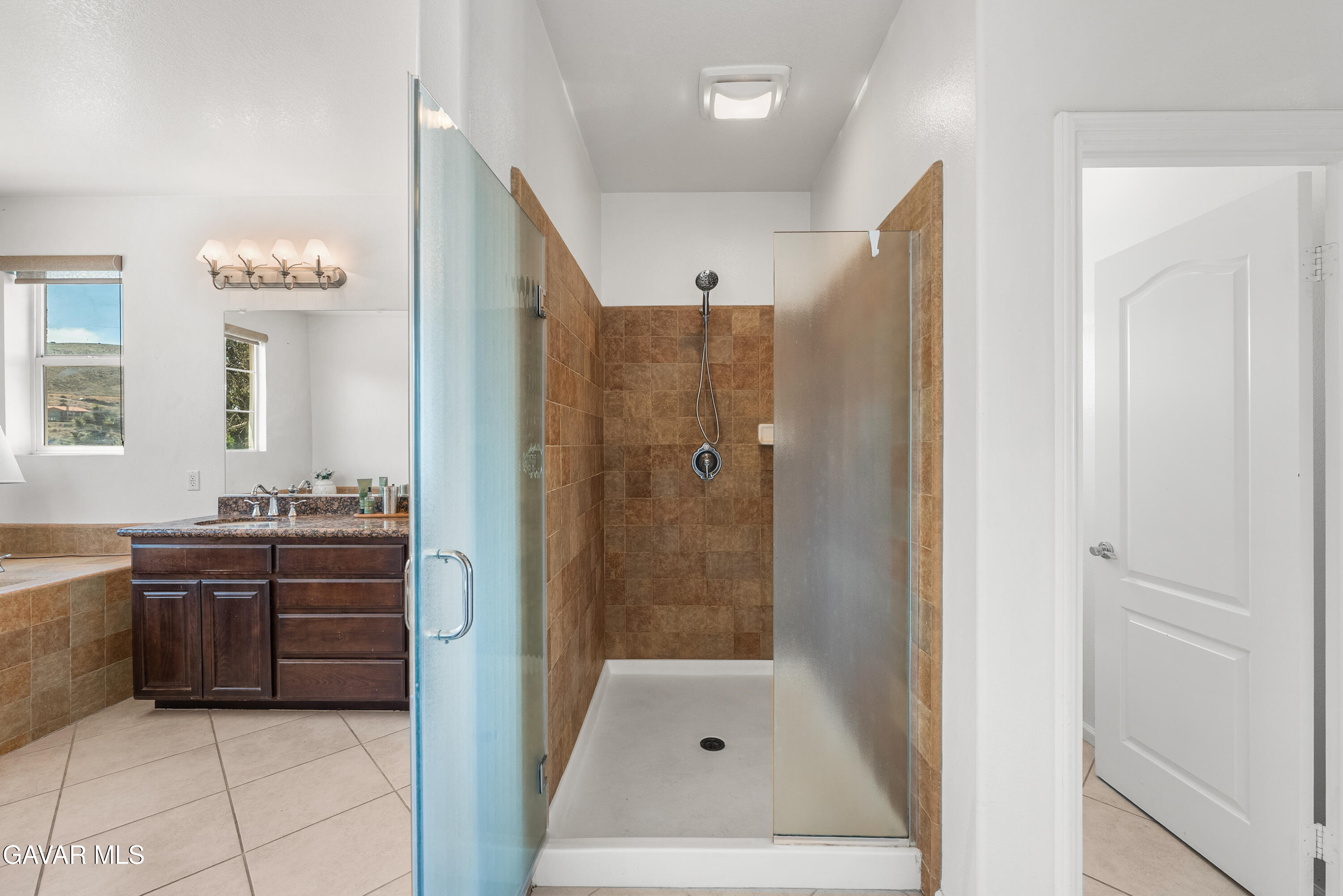 658 Lago Lindo Road Palmdale, CA 93550 - Photo 56 of 91 a bathroom with a granite countertop sink a mirror a bathtub and shower