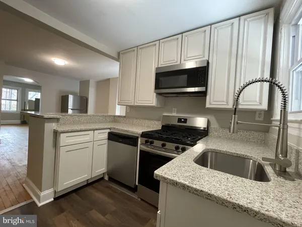 a kitchen with granite countertop a sink stainless steel appliances and white cabinets