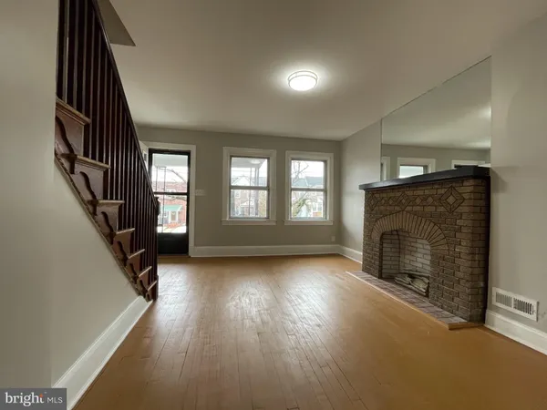 an empty room with wooden floor fireplace and windows