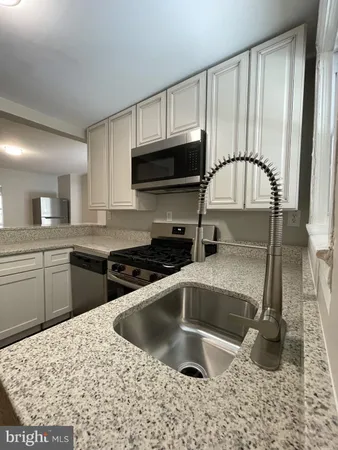 a kitchen with granite countertop a sink a stove and cabinets