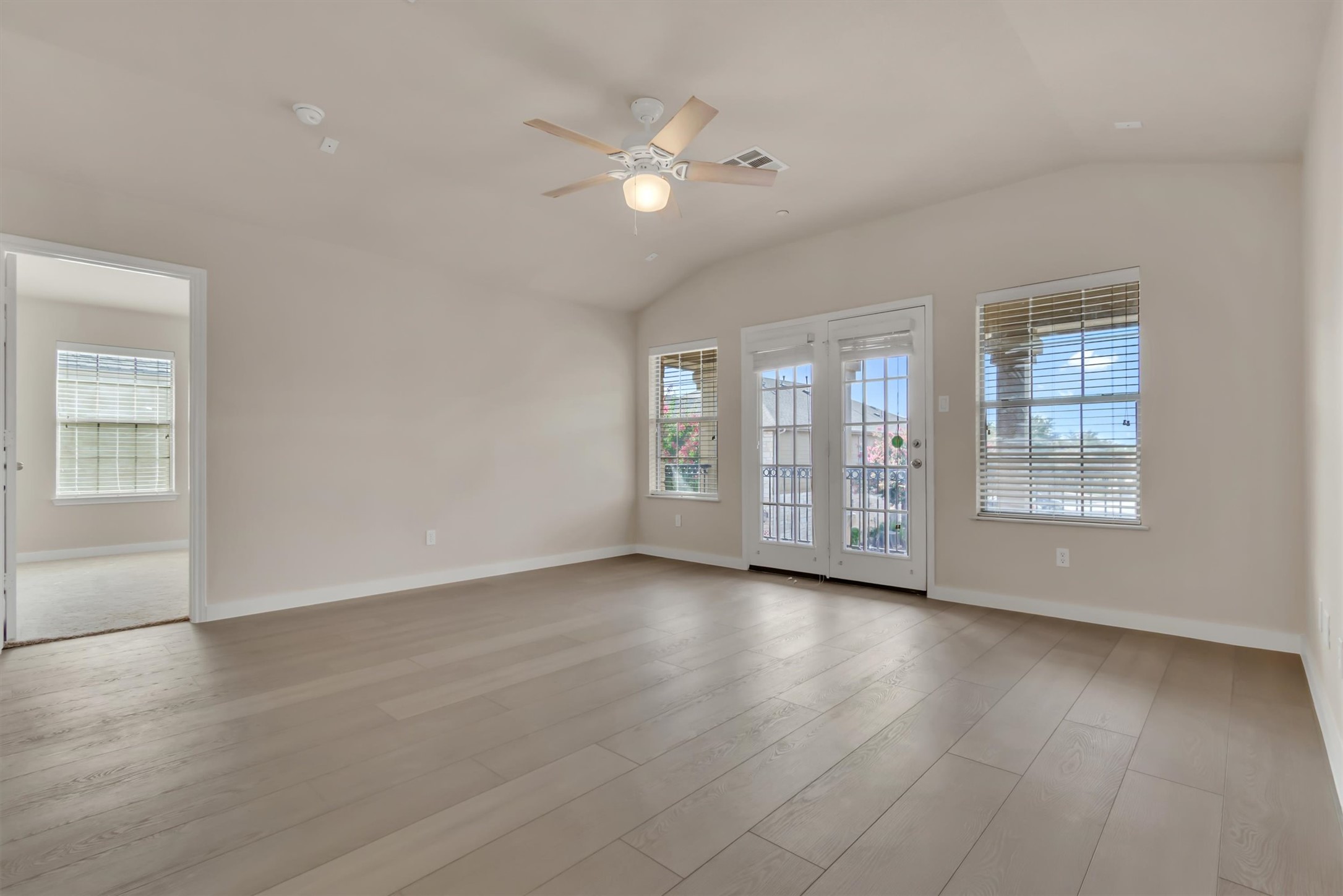 14815 Avery Ranch Boulevard, Unit 2A Austin, TX 78717 - Photo 7 of 27 A well-lit living area features vaulted ceilings, ample natural light, and attractive hardwood-style flooring.
