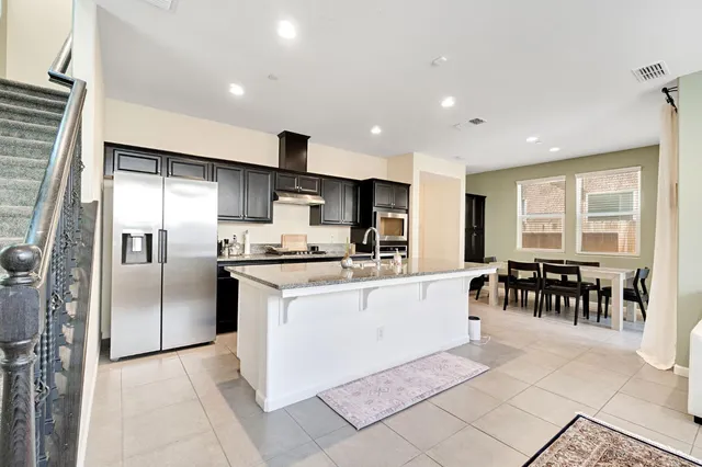 a kitchen with stainless steel appliances kitchen island granite countertop a refrigerator and a sink