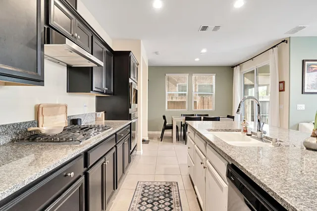 a kitchen with stainless steel appliances granite countertop a sink stove and cabinets