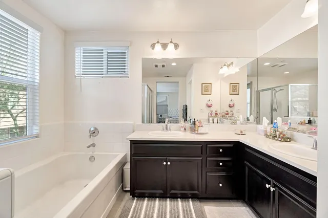 a spacious bathroom with a tub double sink and mirror