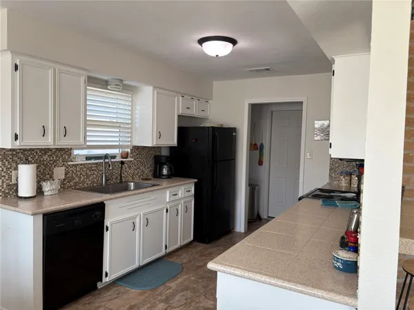 a kitchen with a sink dishwasher a refrigerator and cabinets