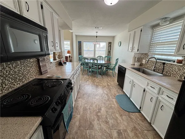 a kitchen with a stove a sink and wooden floor