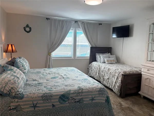 a bedroom with a bed a flat screen tv and a large window