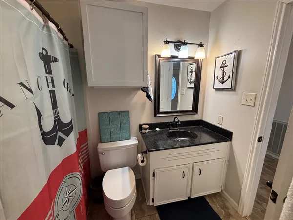 a bathroom with a granite countertop toilet sink and mirror