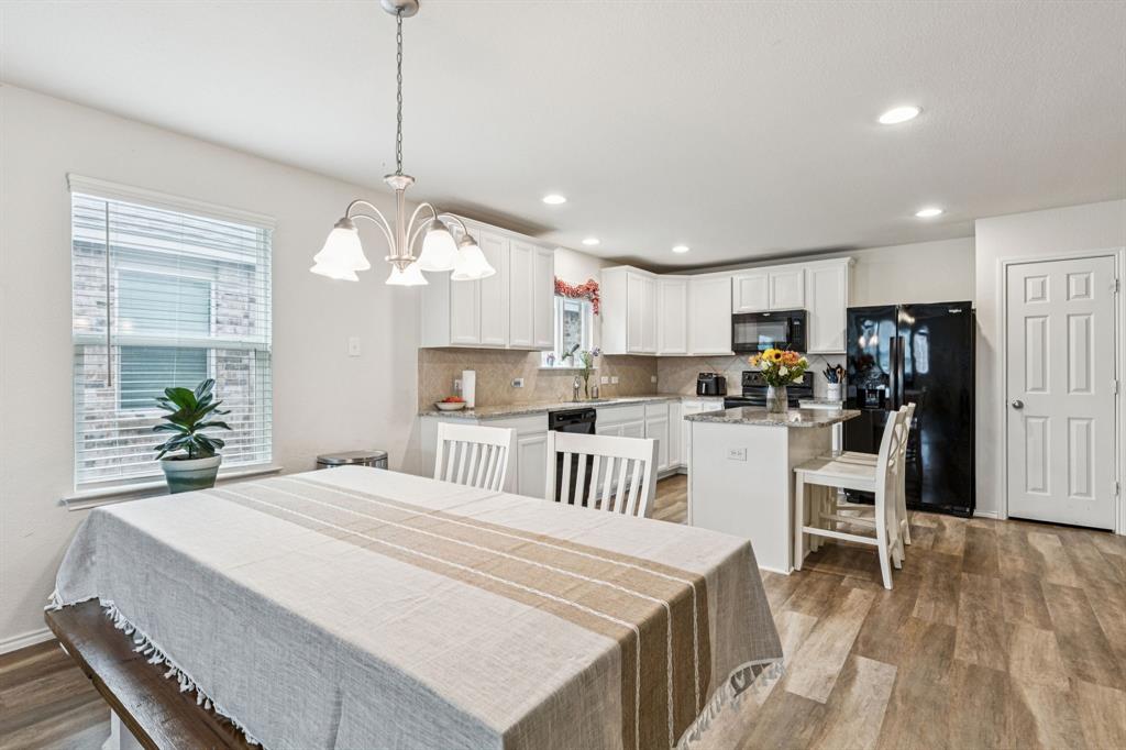 1207 Perrin Drive Forney, TX 75126 - Photo 4 of 20 a kitchen with kitchen island a refrigerator a stove a center island and a wooden floor