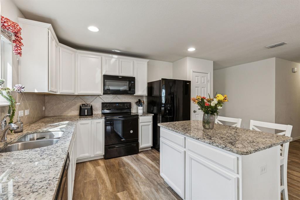 1207 Perrin Drive Forney, TX 75126 - Photo 8 of 20 a kitchen with kitchen island granite countertop stainless steel appliances stove microwave refrigerator and sink