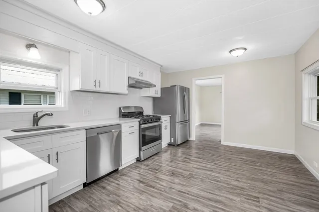 a kitchen with stainless steel appliances a sink cabinets and a wooden floor