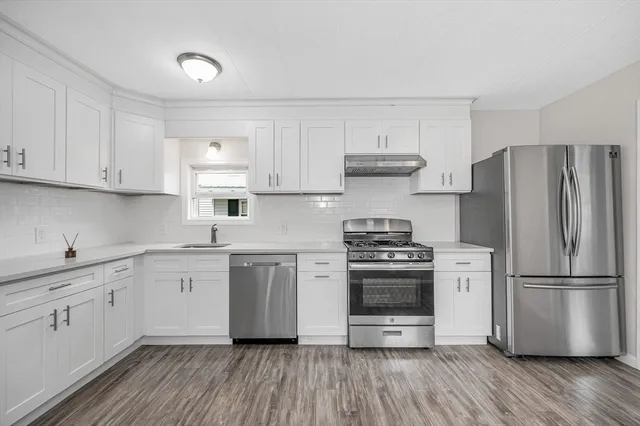 a kitchen with cabinets stainless steel appliances a sink and wooden floor