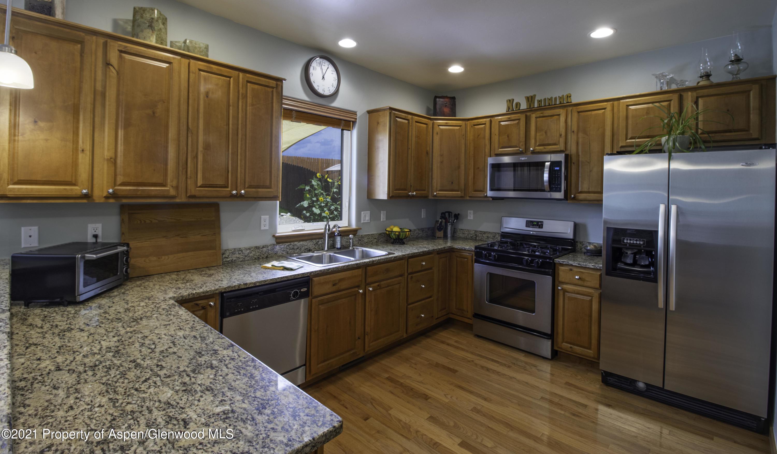 1904 Promontory Circle Rifle, CO 81650 - Photo 5 of 20 a kitchen with stainless steel appliances granite countertop a refrigerator a sink dishwasher a stove top oven a large island with wooden floor and cabinets