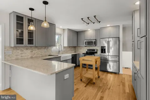 a kitchen with a refrigerator a sink and wooden floor
