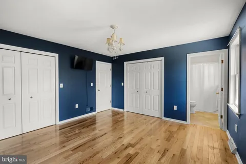 a view of an empty room with wooden floor and a bathroom