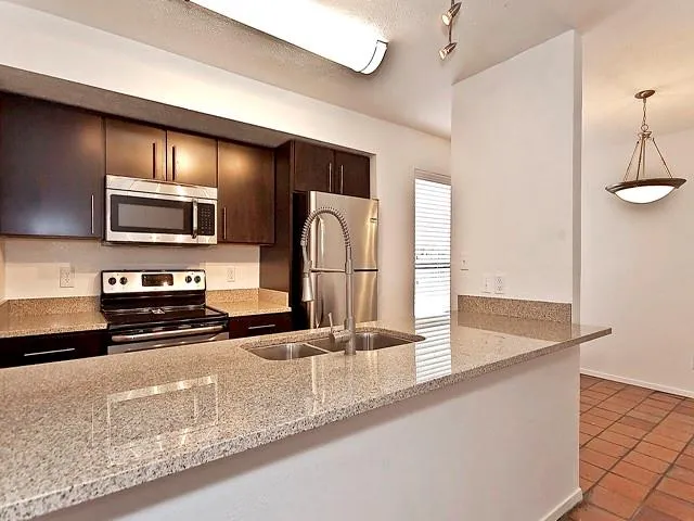 a kitchen with a sink a counter top space cabinets and stainless steel appliances