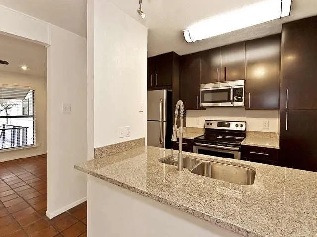 a kitchen with stainless steel appliances kitchen island granite countertop a refrigerator and a sink
