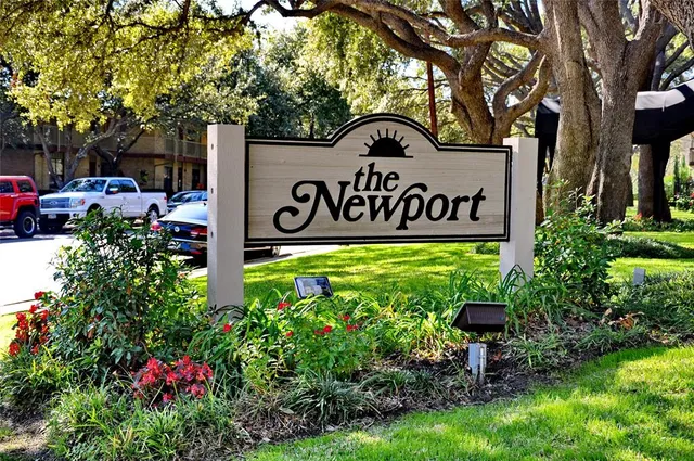 a view of sign board with flower and trees