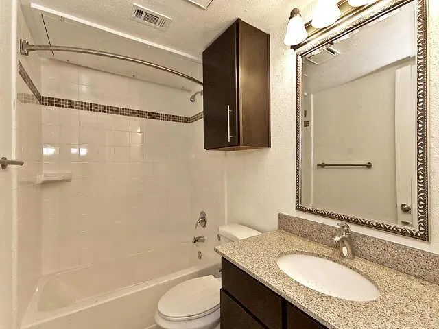 a bathroom with a granite countertop sink toilet and shower