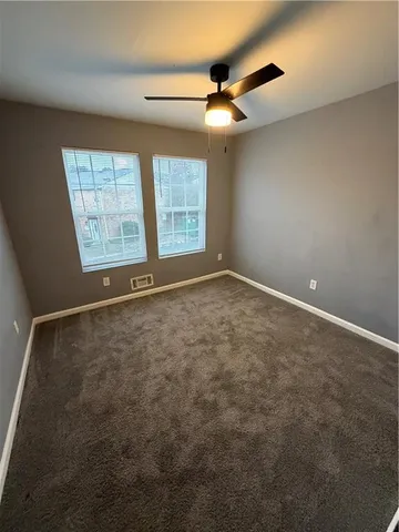 an empty room with windows and chandelier fan