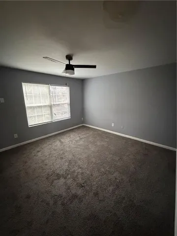 an empty room with windows and ceiling fan