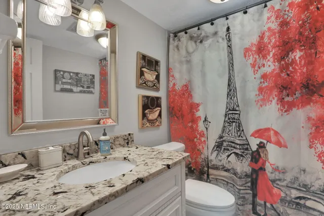 a bathroom with a granite countertop sink mirror vanity and toilet