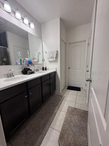 a bathroom with a sink double vanity granite tub shower and a mirror