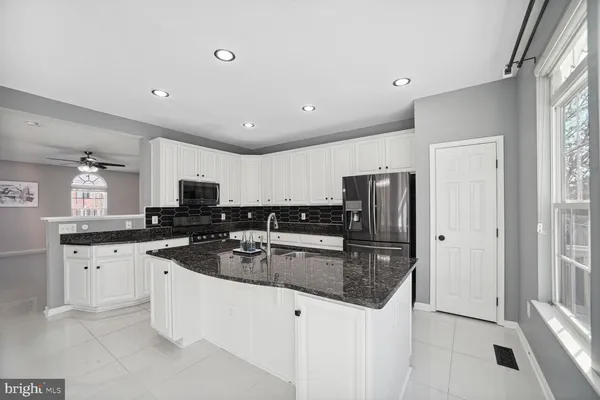 a kitchen with stainless steel appliances granite countertop a sink stove refrigerator and cabinets