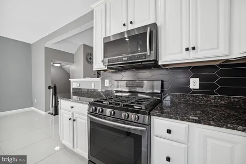 a kitchen with granite countertop white cabinets and stainless steel appliances