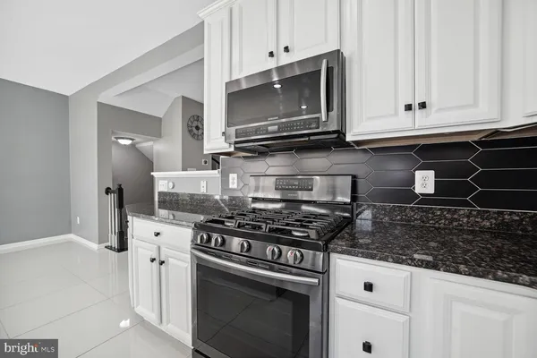 a kitchen with granite countertop white cabinets and stainless steel appliances