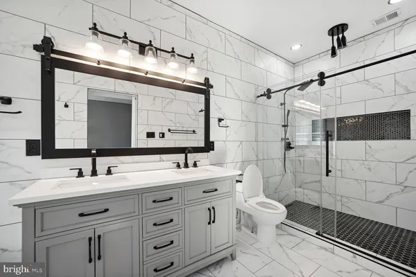 a bathroom with a double vanity sink mirror and toilet