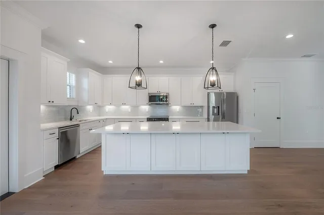 a kitchen with kitchen island white cabinets and stainless steel appliances