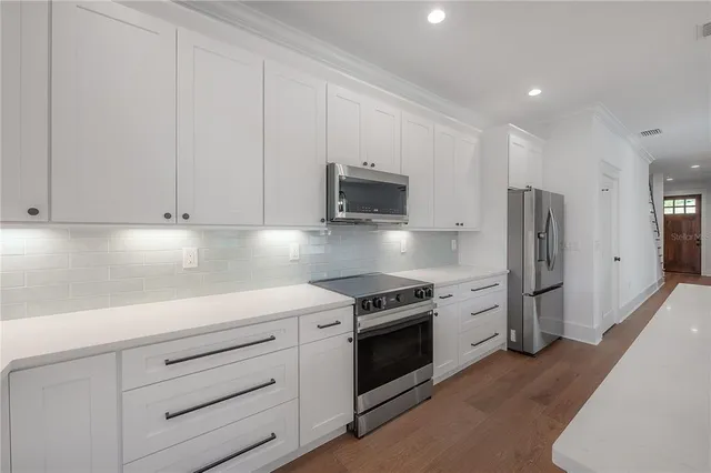 a kitchen with stainless steel appliances white cabinets and a stove top oven