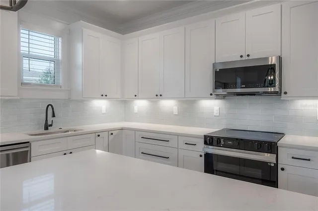 a kitchen with granite countertop a stove a sink and a microwave