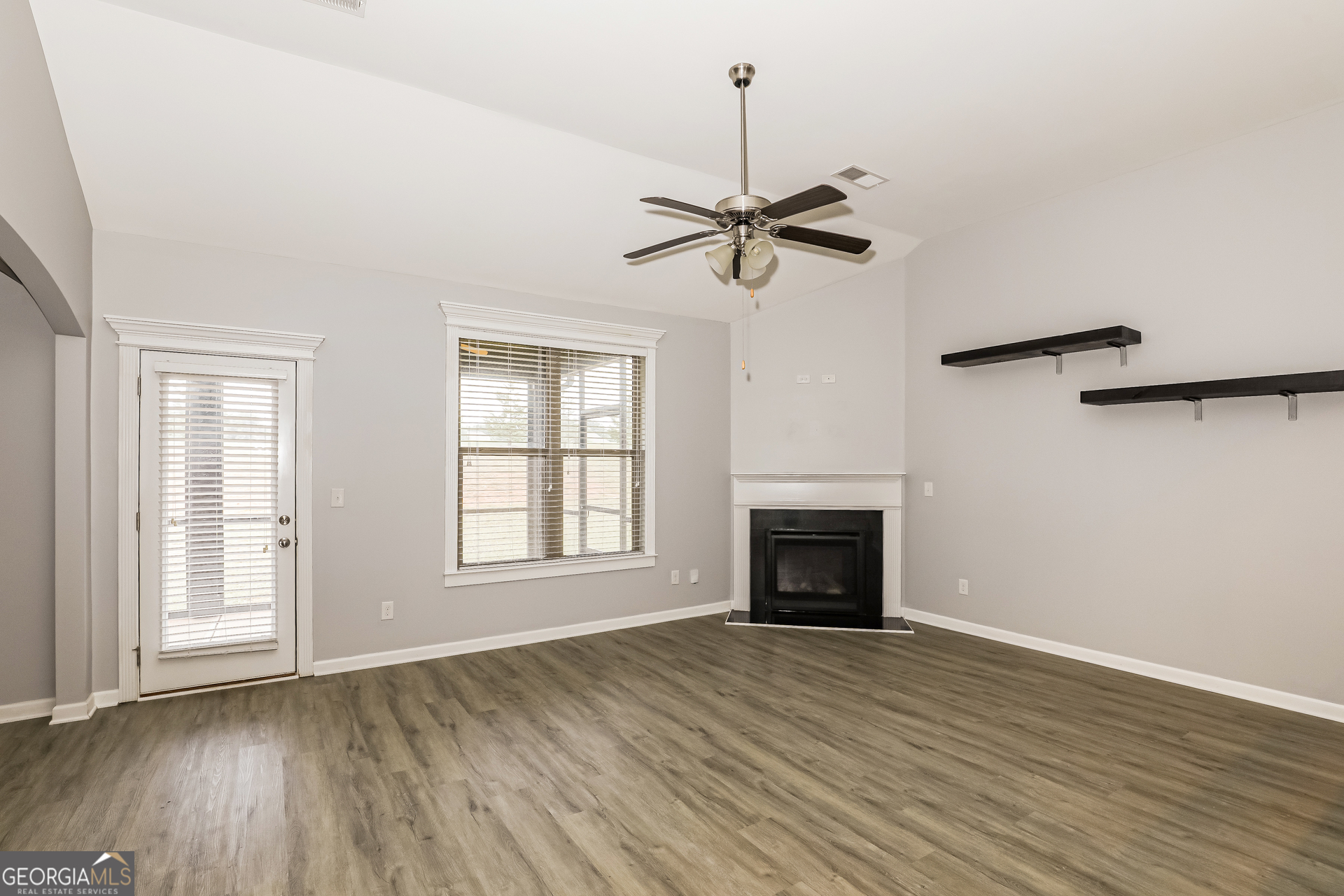 3216 Alhambra Circle Hampton, GA 30228 - Photo 2 of 21 an empty room with windows fireplace and wooden floor